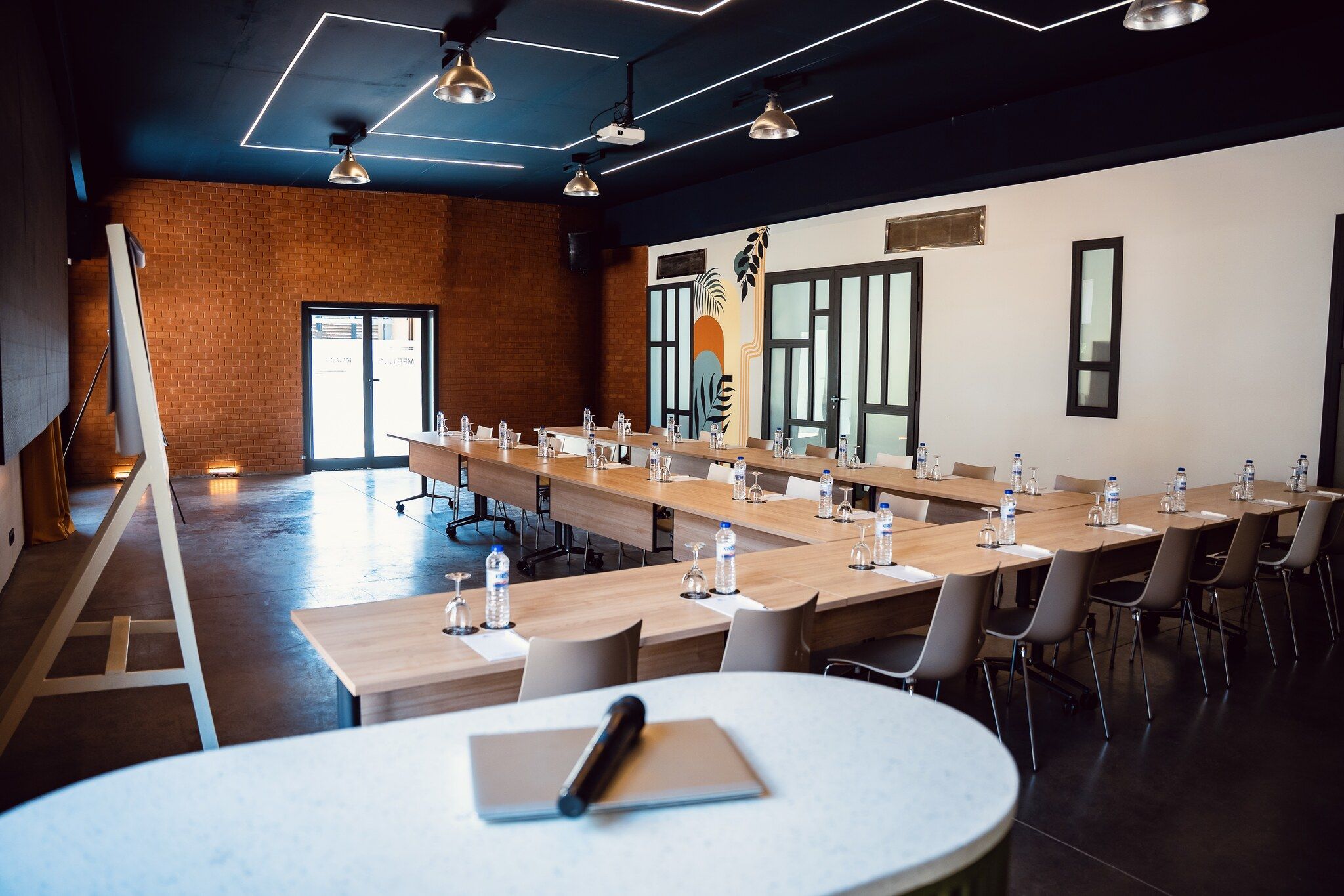 Un salón de conferencias con mesas largas, sillas y una pizarra.