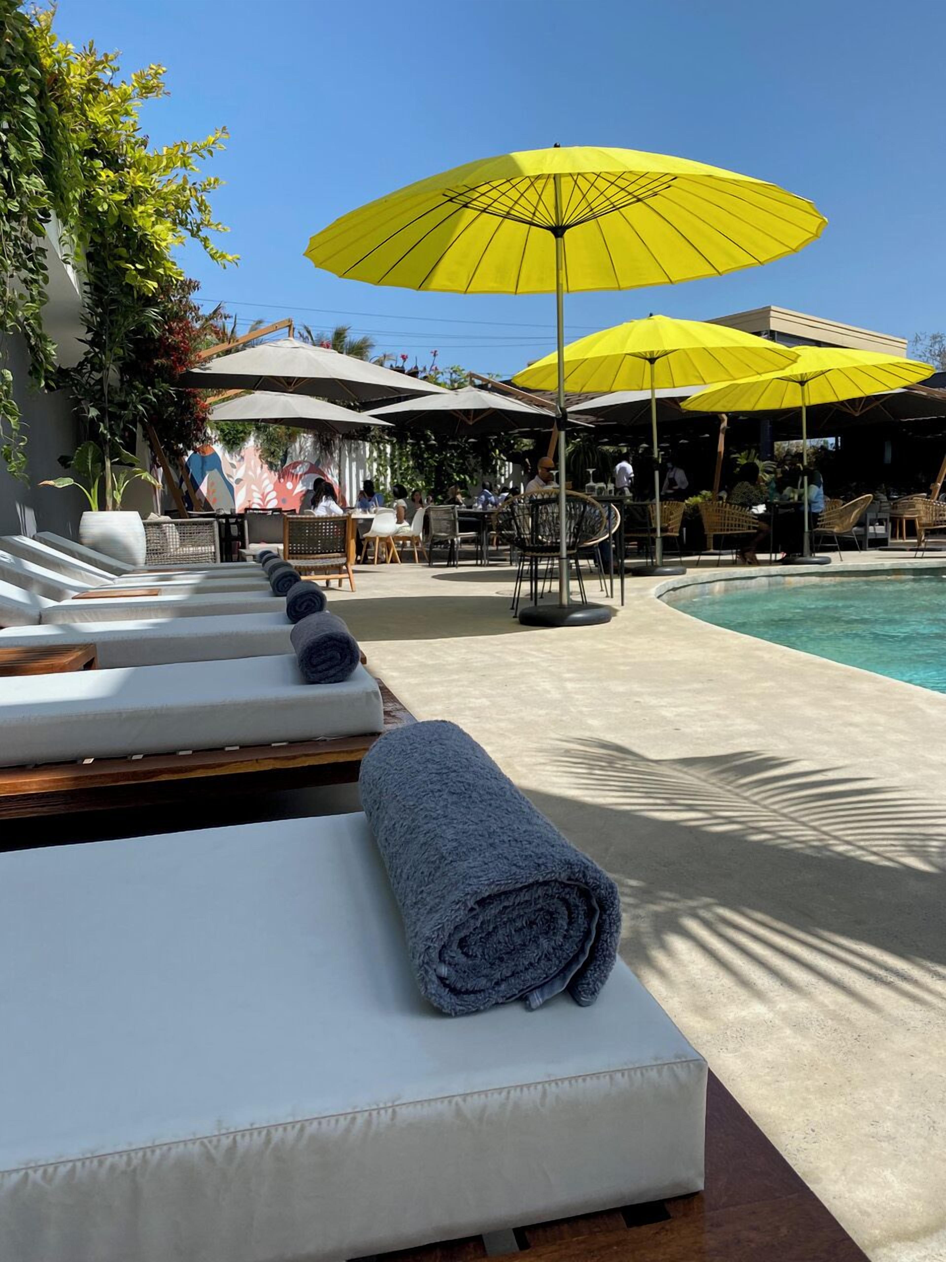 A poolside area with lounge chairs and yellow umbrellas.