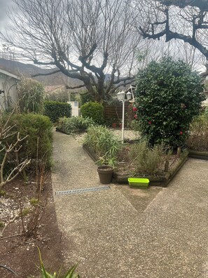 A garden with various plants, a pathway, and a wooden fence. - Hôtel Restaurant Les Marronniers (Thueyts)