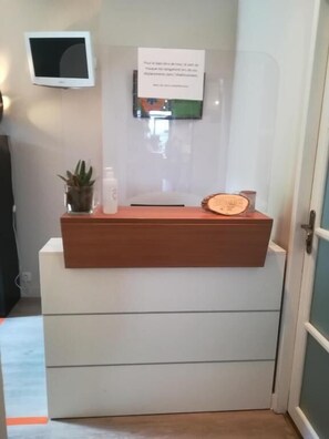 A reception desk with a flat-screen TV mounted on the wall above it. - Hôtel Restaurant Les Marronniers (Thueyts)