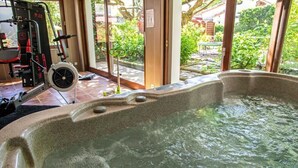 Un jacuzzi con vistas a un gimnasio y follaje exterior.