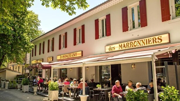 Un restaurante llamado "des MARRONNIERS" con terraza y plantas en macetas.