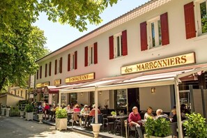 Ein Restaurant namens "des MARRONNIERS" mit Außenbereich und Pflanzen in Töpfen.