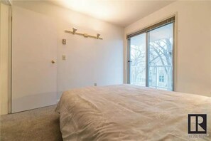 A bedroom with a large window, a bed, a door, and a light fixture. - Modern 2 bed/2 bath Condo in Great location
(Winnipeg)