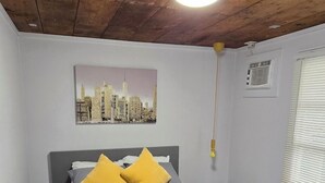 A bedroom with a bed, a cityscape painting, a ceiling fan, and a window with blinds. - La Chiquita is only 3 blocks from downtown. (Coleman)