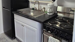 A compact kitchen with a black refrigerator, a stove, and a microwave. - La Chiquita is only 3 blocks from downtown. (Coleman)
