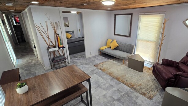 A modern living room with a sofa, a leather armchair, a dining table, and a small side table. There is a window with blinds and a mirror on the wall. - La Chiquita is only 3 blocks from downtown. (Coleman)