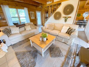 A cozy living room with two sofas, a coffee table, and a staircase.