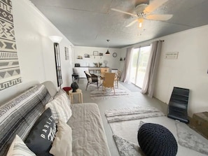 Un salon confortable avec un canapé, un coin repas avec des chaises et un ventilateur de plafond.