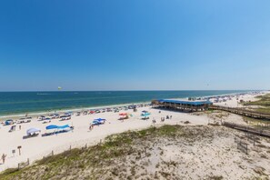 A beach with a pier and beach umbrellas. - Beachfront 2BR | Private Balcony, Pool | Gulf Views (Gulf Shores)