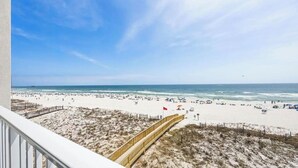 A beach with a wooden boardwalk leading to the shore, sandy dunes, and a clear blue sky. - Beachfront 2BR | Private Balcony, Pool | Gulf Views (Gulf Shores)