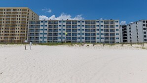 A beachfront hotel with multiple floors, balconies, and a sandy beach in the foreground. - Beachfront 2BR | Private Balcony, Pool | Gulf Views (Gulf Shores)