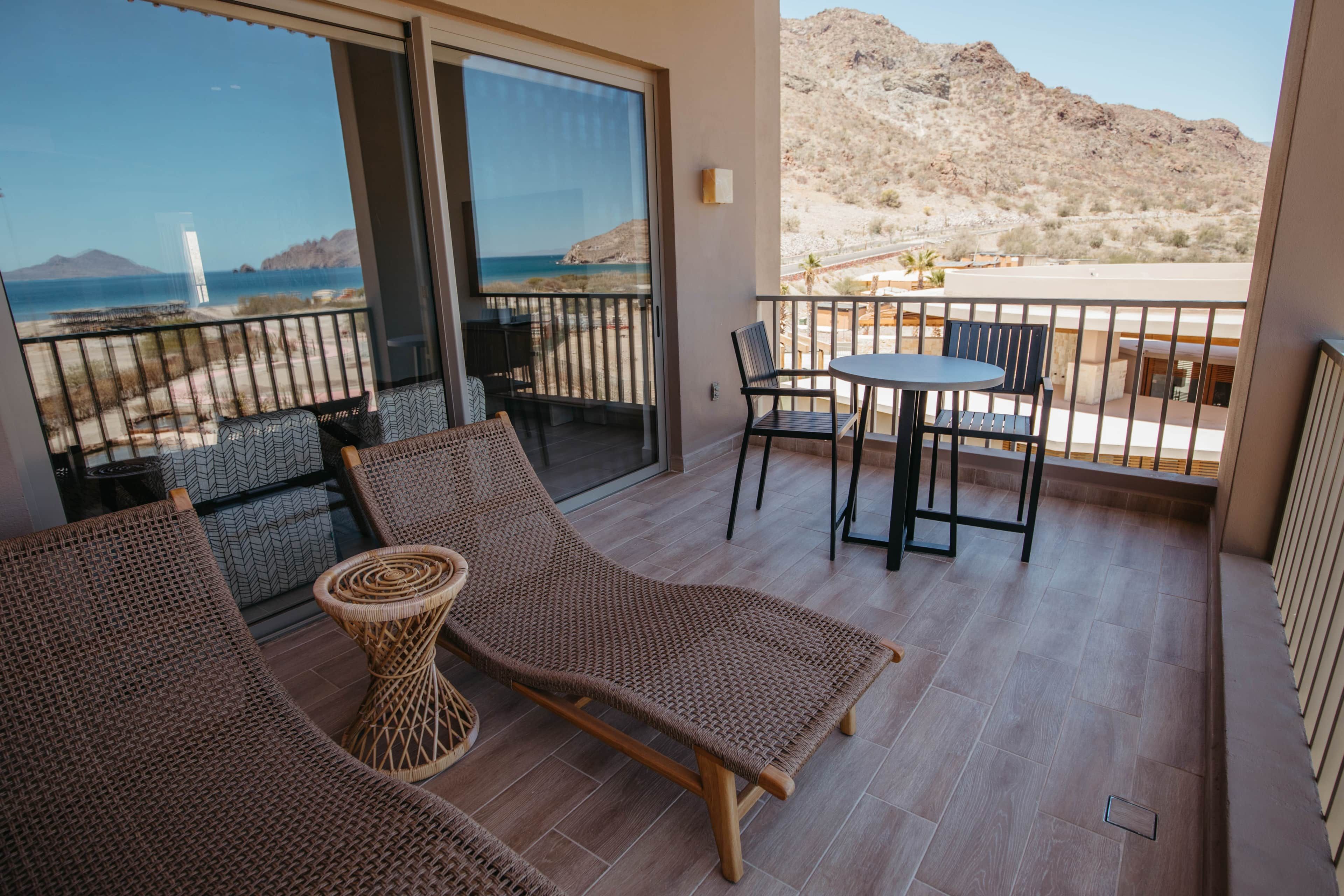A balcony with wicker furniture, a table, and chairs.