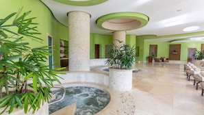 Zona d'spa amb banyera d'hidromassatge, parets verdes i seients.
