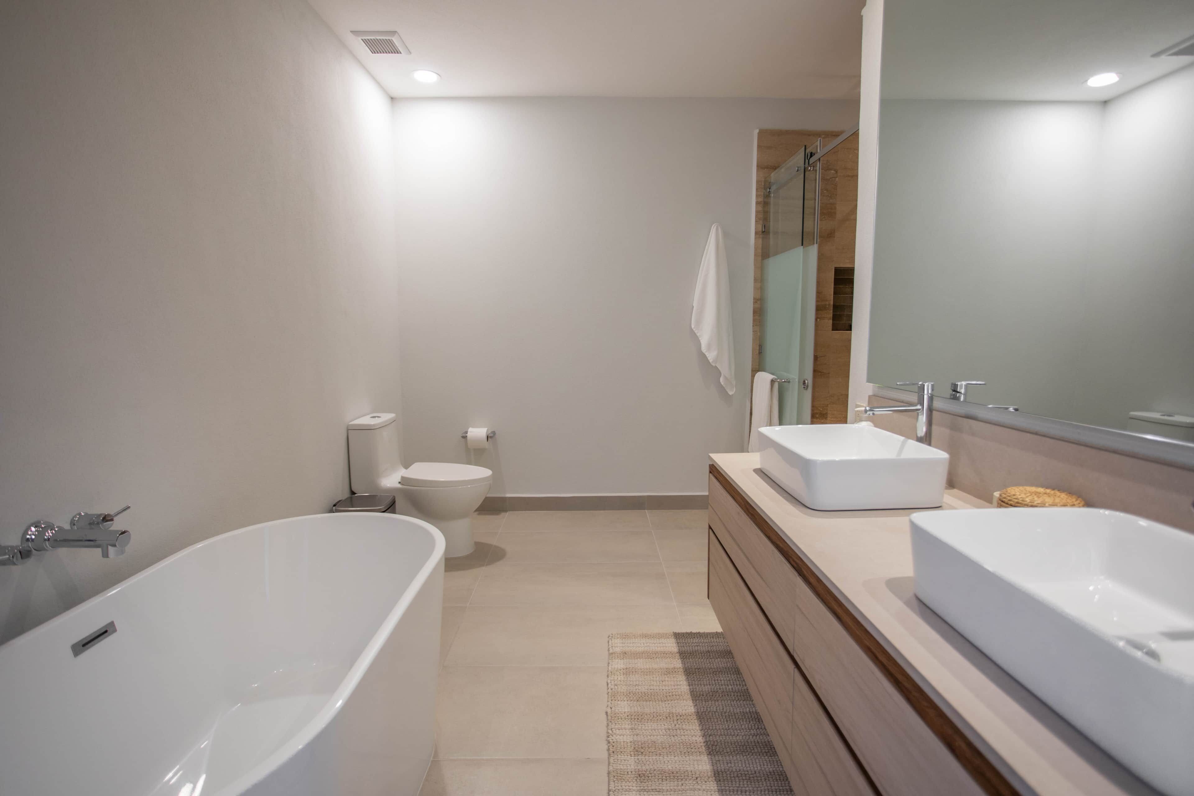 A modern bathroom with a freestanding bathtub, a vanity with a mirror, and a toilet.