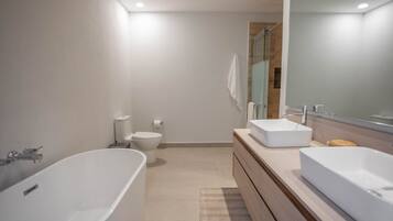 A modern bathroom with a freestanding bathtub, a vanity with a mirror, and a toilet.