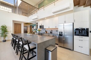 Una cocina moderna con una isla central, electrodomésticos de acero inoxidable y un comedor con sillas.