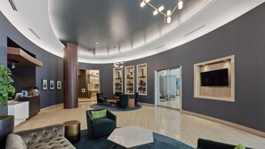 A modern lobby with a curved ceiling, a reception desk, seating areas, and a television. - Austin Modern 1BD 1BA Apartment (Austin)