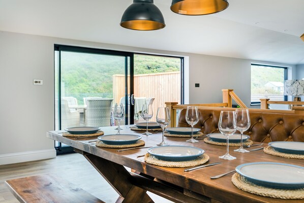 A dining area with a large table set for six, featuring woven placemats and blue plates. - Breakers View (Wadebridge)