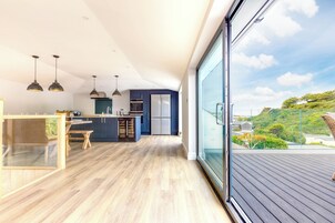 Una cocina moderna con una isla grande, armarios azul oscuro y una puerta corredera de vidrio que da a una terraza.