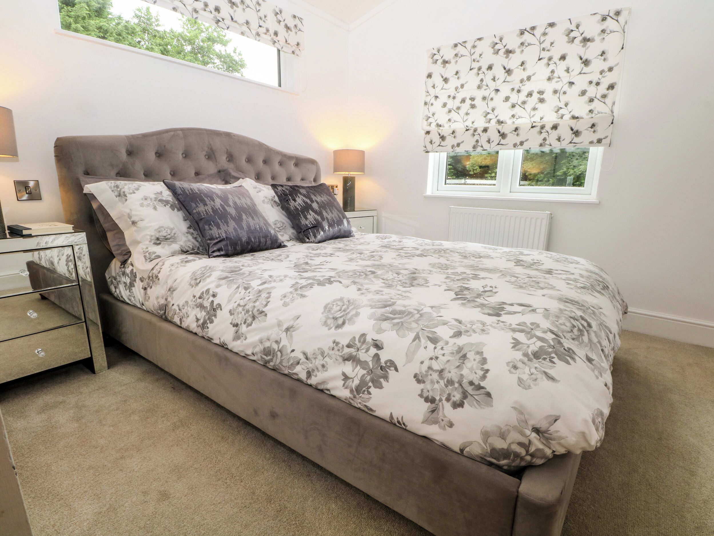 A bedroom with a bed, nightstands, a window with a view, and a radiator.