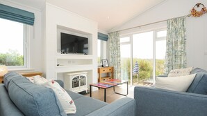 Una sala de estar con chimenea, televisión y vistas al exterior.