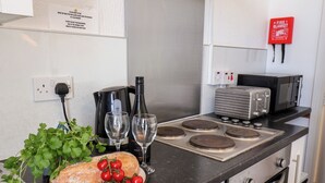 A kitchen with a stove, toaster, and a fire blanket on the wall. - 6 Beach View @ Beaconsfield House (Bridlington)