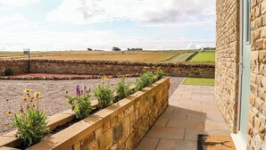 A stone building with a stone wall and a flower bed in front. - Forestside View (Bishop Auckland)