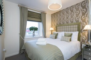 Relax in a spacious room with a large bed, nightstand, and window with curtains.