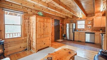 A log cabin interior with a kitchen, dining area, and a fireplace.