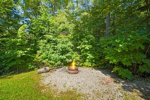 A campfire in a forested area with a gravel path.