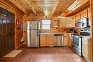 A kitchen with wooden cabinets, stainless steel appliances, and a window.
