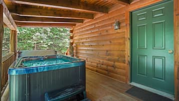 Une cabane en bois avec un jacuzzi et une porte verte.