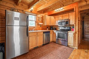 A kitchen with wooden cabinets, stainless steel appliances, and a tiled floor.