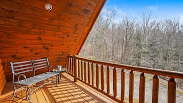 Une terrasse en bois avec un banc et une table, donnant sur une zone boisée.