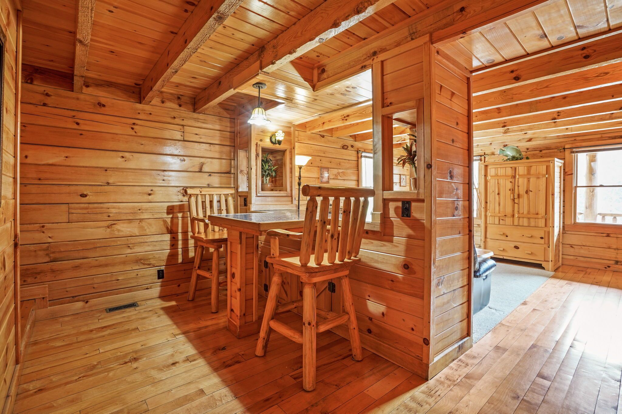 A wooden interior with a dining table and chairs, a bench, and a cabinet.