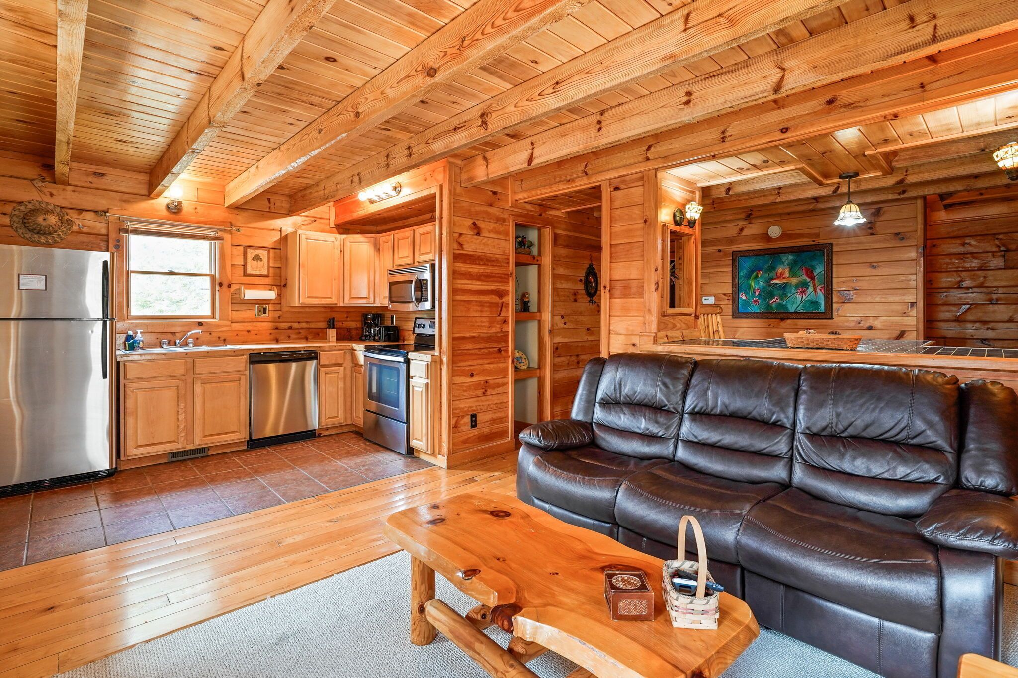 A wooden interior with a kitchen, a leather sofa, and a dining table.