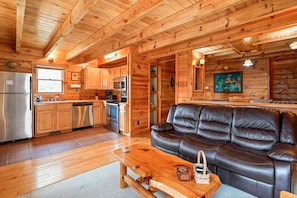 A wooden interior with a kitchen, a leather sofa, and a dining table.