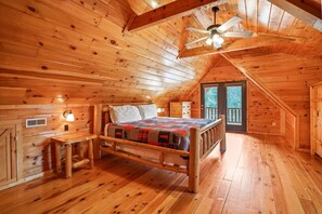 A wooden cabin bedroom with a bed, a nightstand, a bench, and a ceiling fan. - The Hemlock | Hocking Hills, Romantic, Hot Tub (Rockbridge)