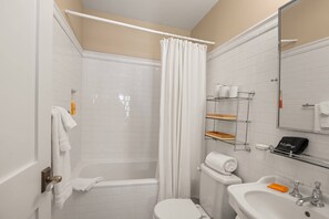 A bathroom with a shower, toilet, sink, and a mirror.