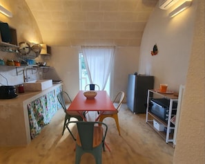 Una cocina compacta con una mesa de comedor, sillas y un refrigerador.