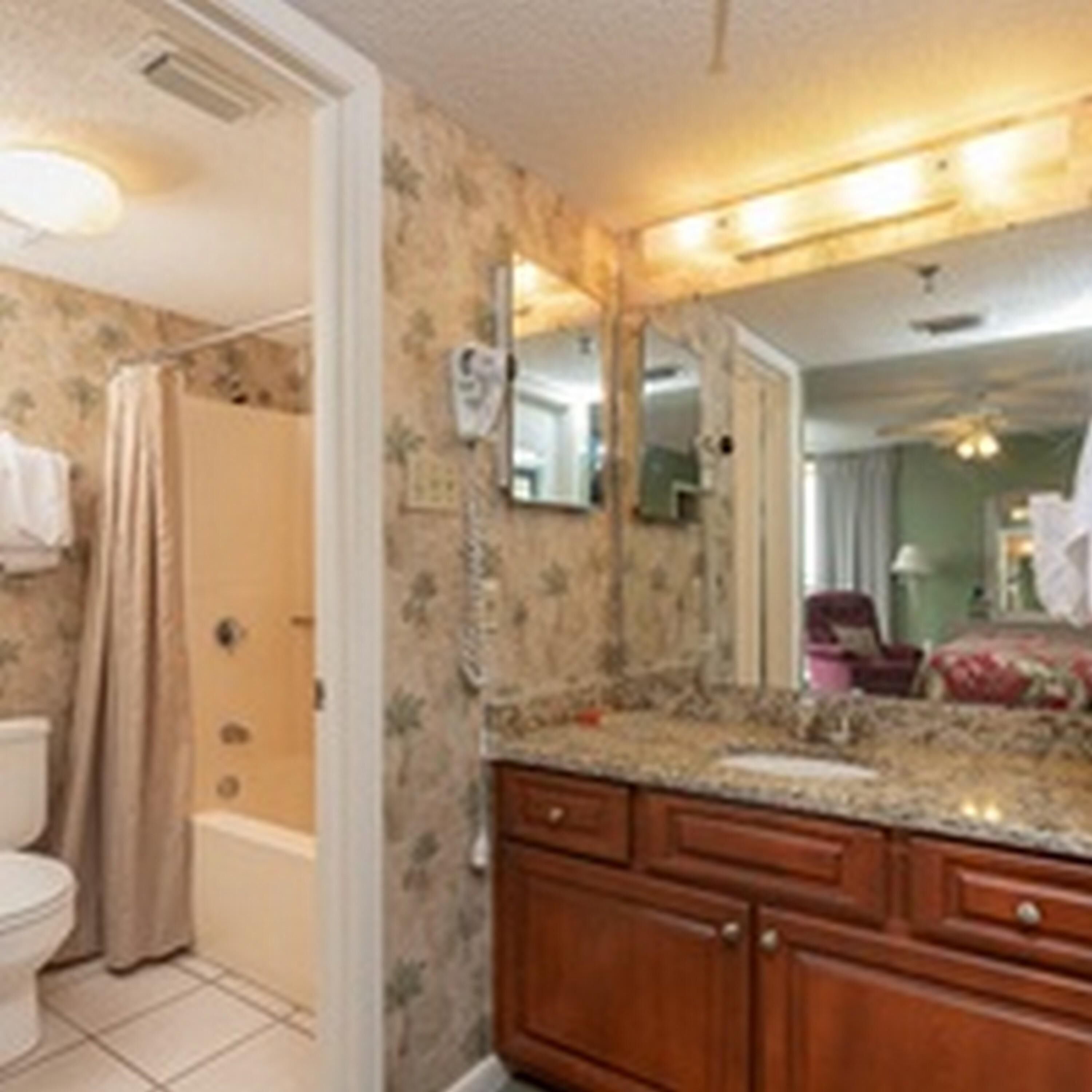 A bathroom with a shower, toilet, and vanity with a mirror.