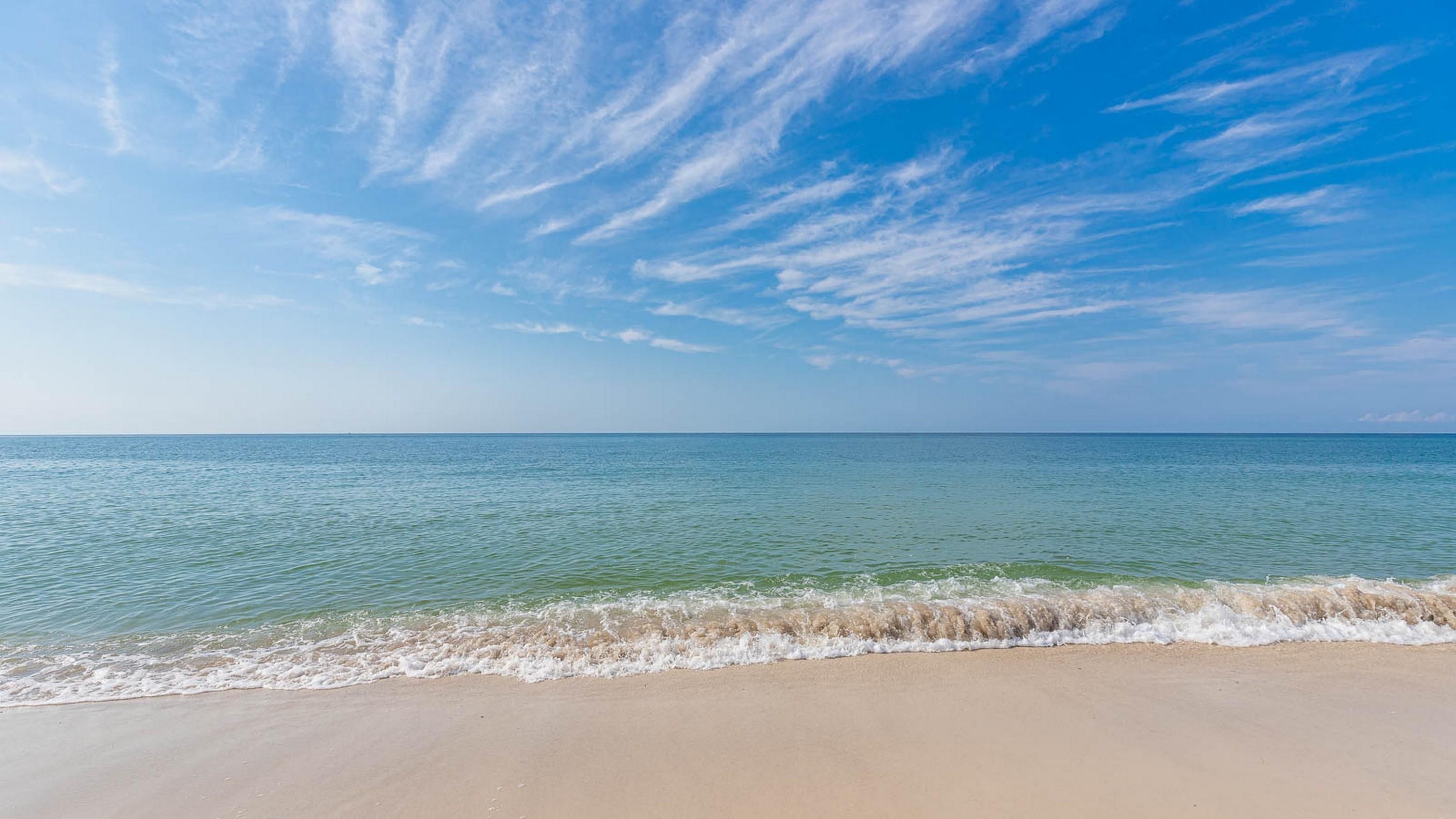 Una playa con cielos despejados y agua tranquila.