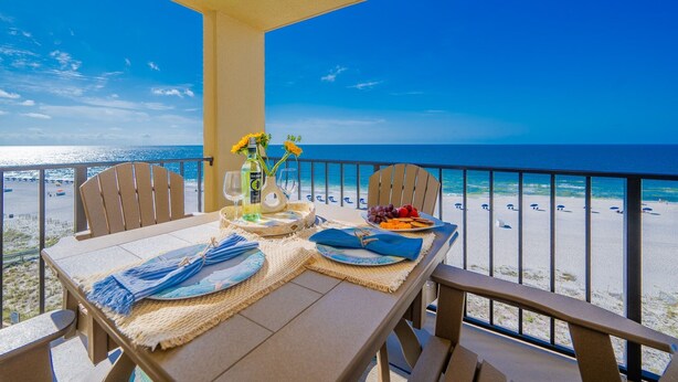 Varanda com mesa posta para dois, com vista para a praia.