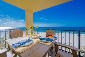 A balcony with a table set for two, overlooking a beach. - Phoenix III by Brett Robinson Vacations (Orange Beach)