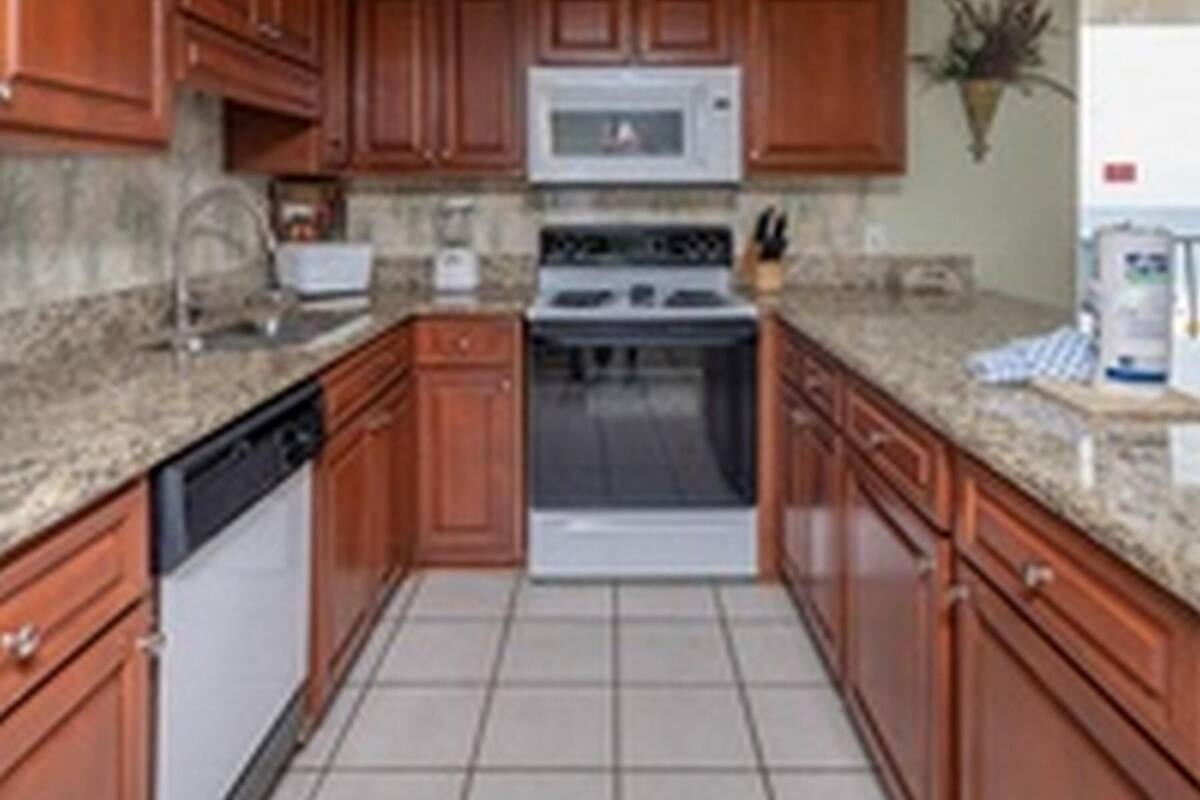 Una cocina con armarios de madera, microondas, estufa y lavavajillas.