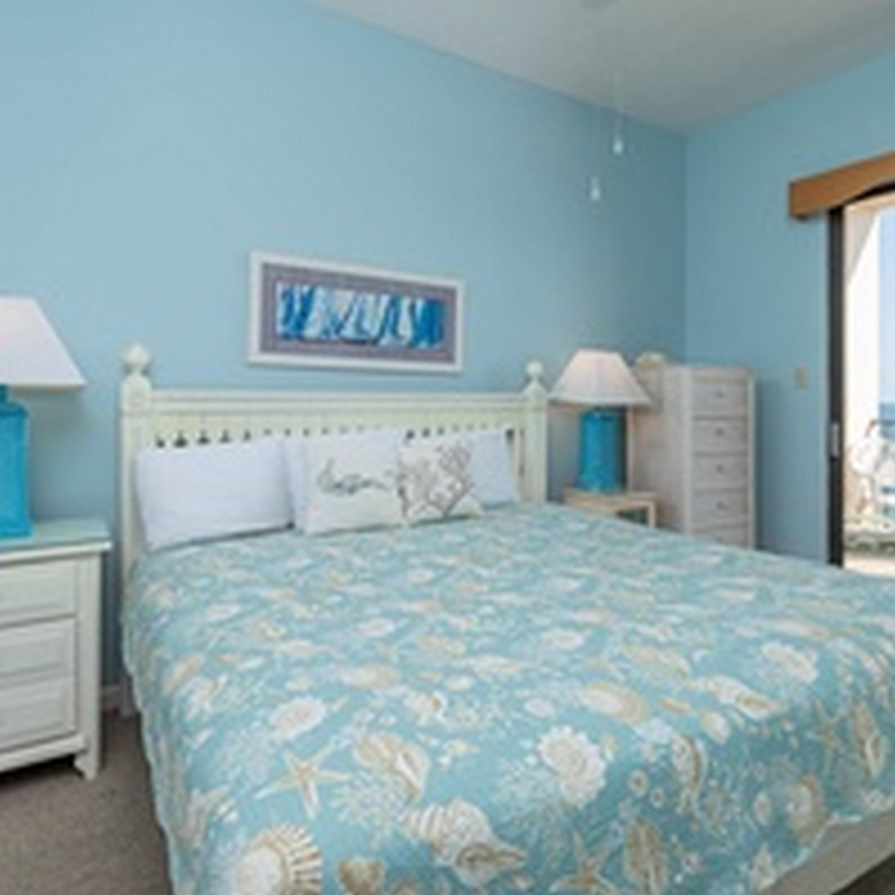 Une chambre à coucher avec un lit, des tables de chevet, une commode et un tableau au mur.