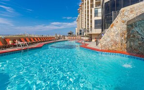 A swimming pool with lounge chairs and a stone wall. - Phoenix III by Brett Robinson Vacations (Orange Beach)