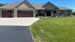 A two-story house with a stone facade, a large garage, and a well-maintained lawn. - Plan for EAA ! Executive ranch, only 13 miles away  (Neenah)