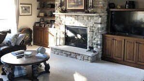 A living room with a stone fireplace, a television, and a ceiling fan. - Plan for EAA ! Executive ranch, only 13 miles away  (Neenah)